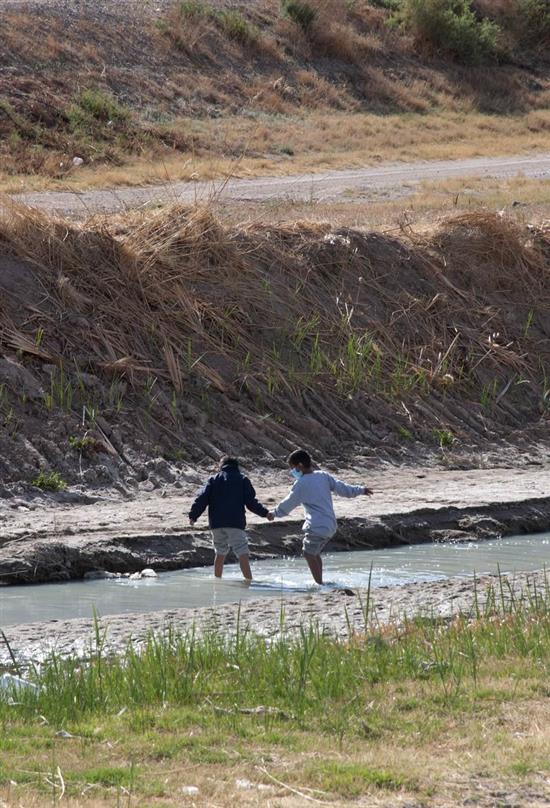2021年3月27日，两名来自危地马拉的移民儿童在跨越美墨边境的里奥格兰德河。